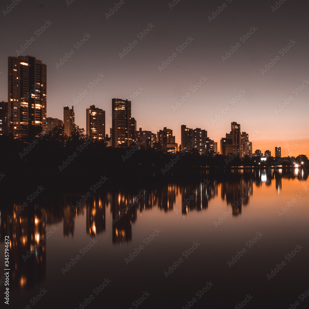night in the city reflected in the lake with orange sunset