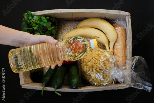 Volunteer collecting food into donation box indoors.Top view of a food box on a black background