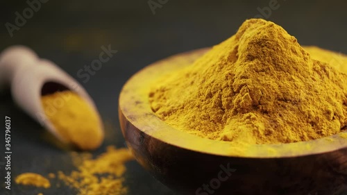 Turmeric or turmeric powder in a wooden bowl blowing in the wind. Cooking ingredients, flavor.