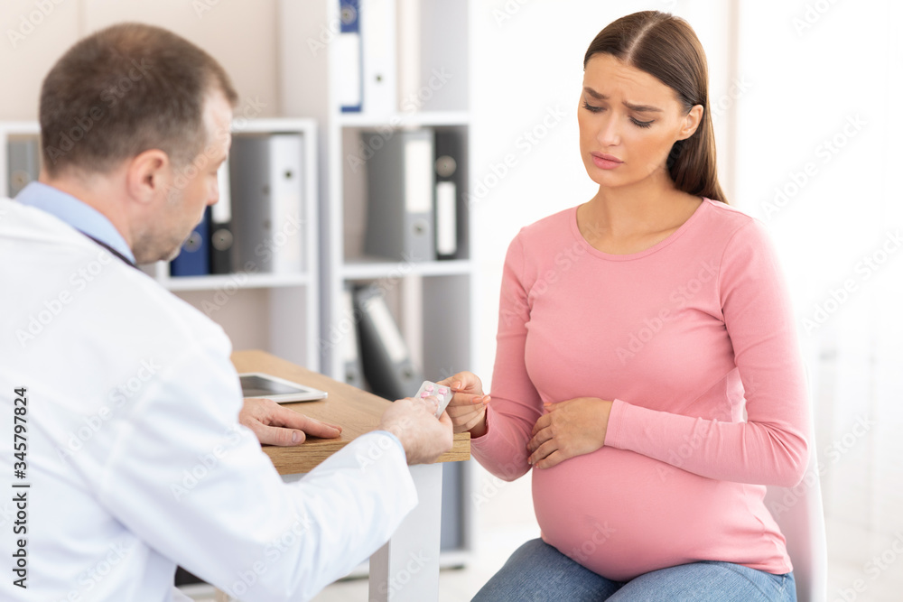 Mature experienced doctor giving pills to pregnant patient Mature experienced doctor giving pills to pregnant patient