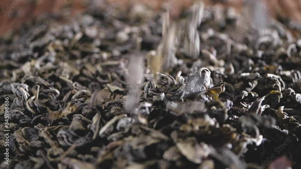 Falling tea leaves on wooden background, in slow motion
Falling tea leaves on wooden background, in slow motion