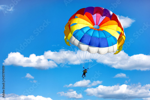 Obraz na plátně Gliding using a parachute on the background of cloudy blue sky.