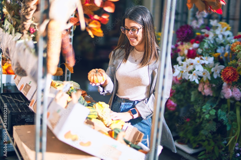 Fototapeta premium Young beautiful woman smiling happy and confident. Standing with smile on face at florist