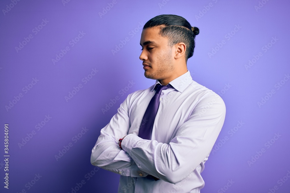 Young brazilian businessman wearing elegant tie standing over isolated purple background looking to the side with arms crossed convinced and confident Young brazilian businessman wearing elegant tie standing over isolated purple background looking to the side with arms crossed convinced and confident