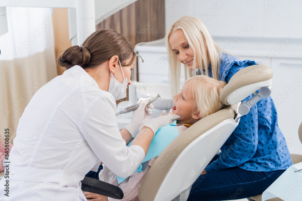 Obraz premium A small girl on the dental hygiene procedure at the dentist's of