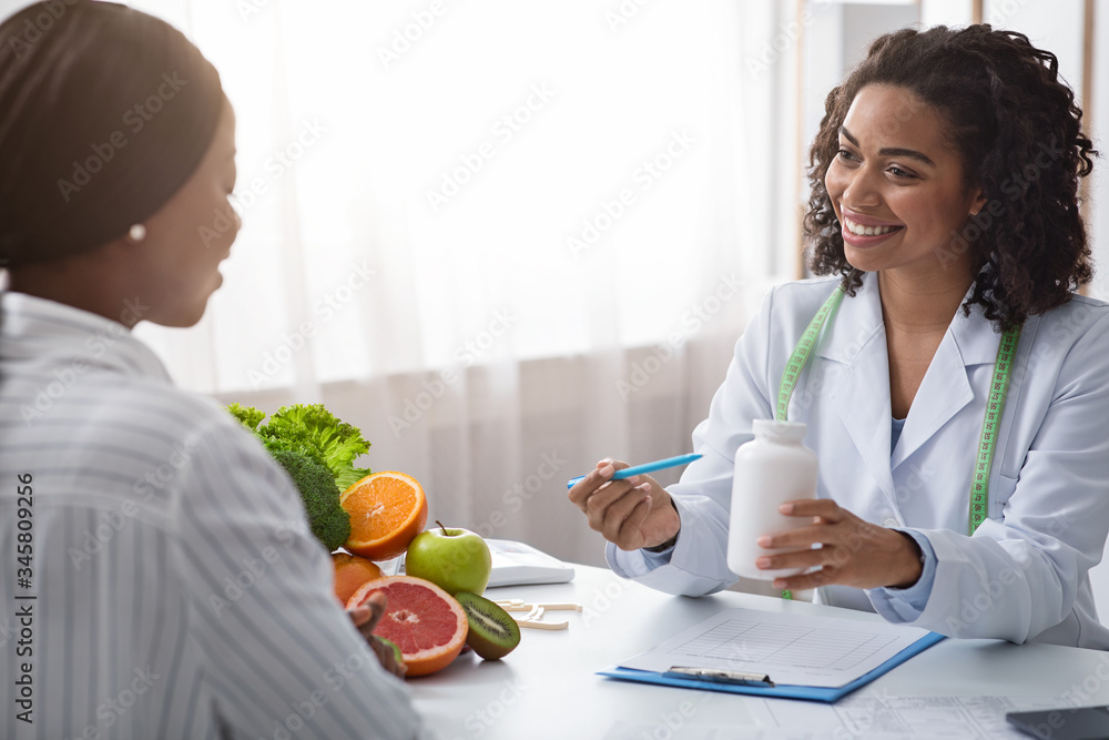 Black woman dietologist recommending tablets to female patient Black woman dietologist recommending tablets to female patient