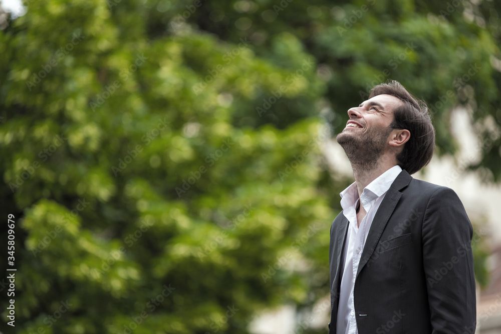 Attractive young businessman standing in nature, looking satisfied and accomplished Attractive young businessman standing in nature, looking satisfied and accomplished