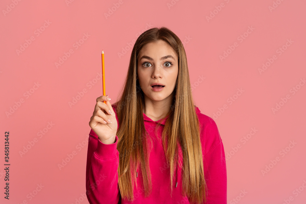 Obraz premium Shocked teenager girl with open mouth raises pencil up