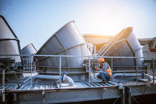 A engineer under checking the industry cooling tower air conditioner is water cooling tower air chiller HVAC of large industrial building to control air system. photo