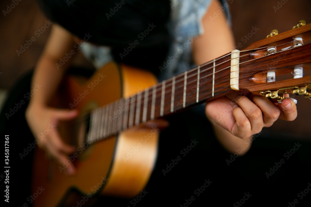 Woman observes and removes a classic brown guitar from a black case