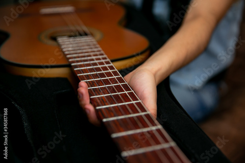 Woman observes and removes a classic brown guitar from a black case