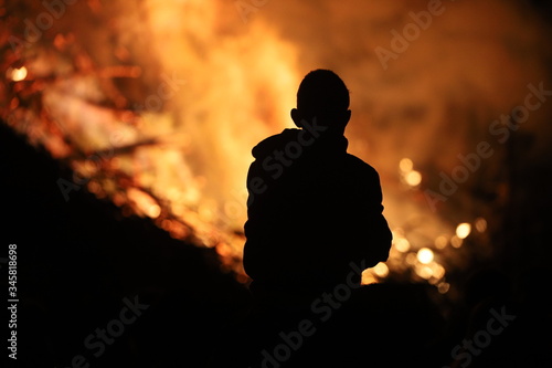 A silhouette of a child watching a large fire