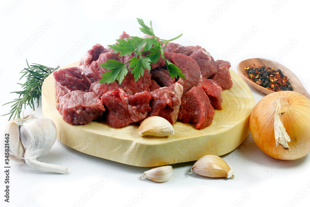 pile of cube chopped pile raw diced beef cubes with spices on wooden board isolated over white background