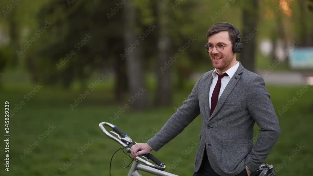 stylish young man in a business suit with a bicycle listening to music in headphones stylish young man in a business suit with a bicycle listening to music in headphones