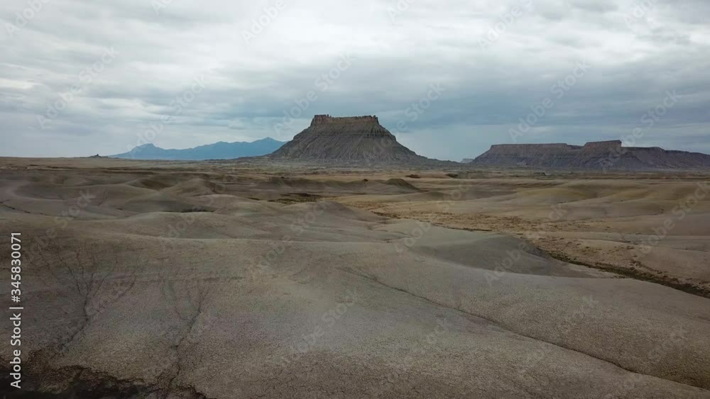 Utah Desert Badlands. Aerial View of Alien Lifeless Landscape and Butte Rock Formations Under Cloudy Sky Utah Desert Badlands. Aerial View of Alien Lifeless Landscape and Butte Rock Formations Under Cloudy Sky