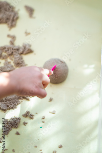 Child's hand playing with kinetic sand in preschool. The development of fine motor concept. Creativity Game concept.