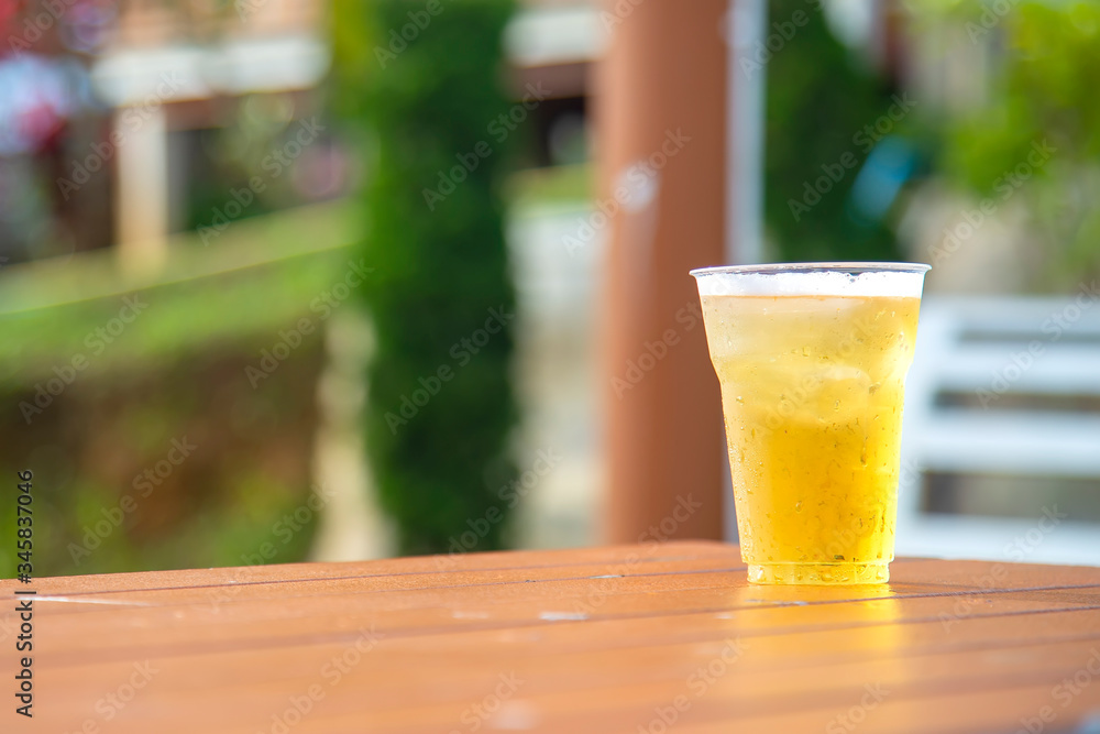 Beer in glass is placed on wooden table in the resort.Beer in a plastic glass with bubble placed on the floor near the pool in the evening for a party. Beer in glass is placed on wooden table in the resort.Beer in a plastic glass with bubble placed on the floor near the pool in the evening for a party.