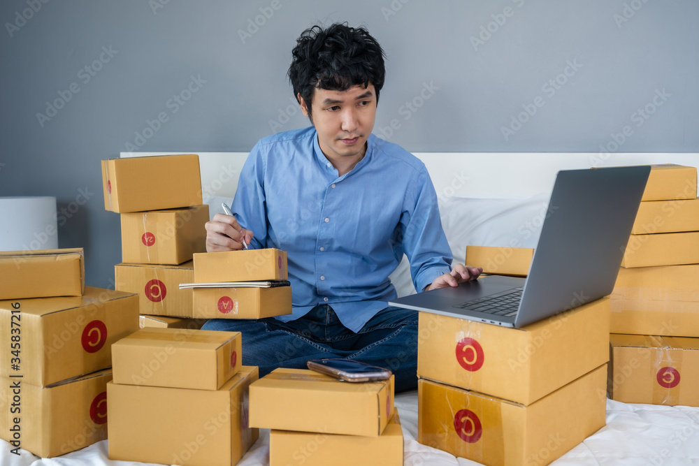 man working and using laptop computer to selling product online on a bed at home man working and using laptop computer to selling product online on a bed at home