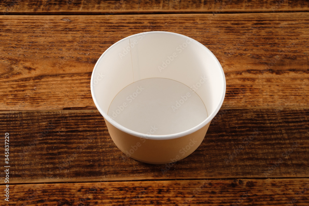 Big brown paper plate isolated on wooden background. Eco-friendly disposable food packaging. Preserving nature and recycling concept. Big brown paper plate isolated on wooden background. Eco-friendly disposable food packaging. Preserving nature and recycling concept.