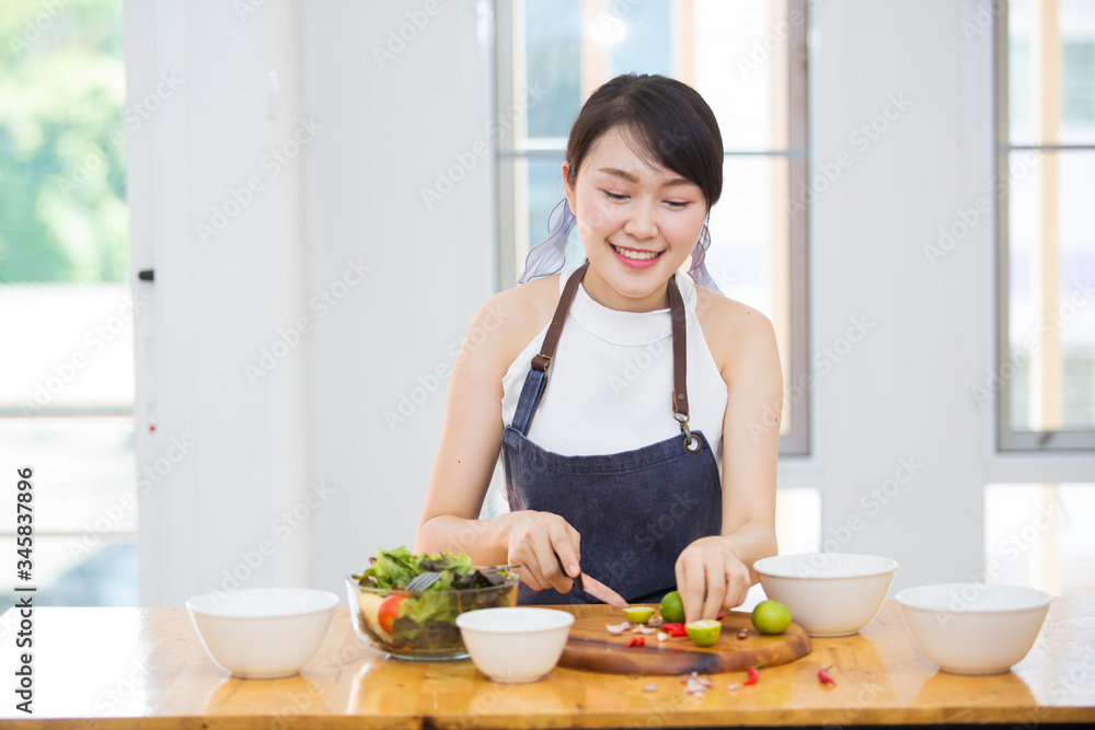 Beautiful Asian women, beautiful smiles, good health, beautiful teeth, eating salad vegetable when working at home.