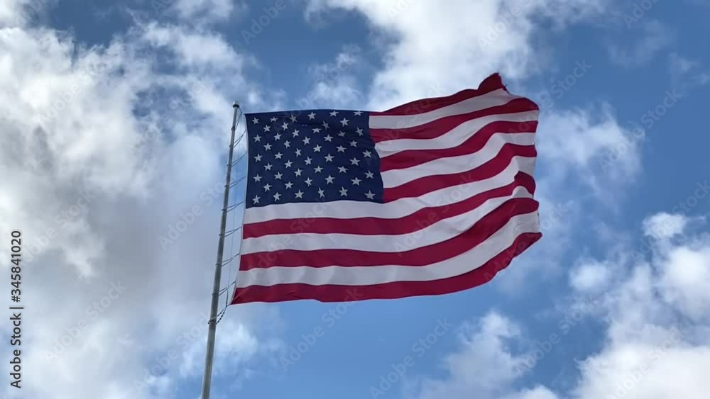 United States flag flying in breeze, blue sky and cloudy background, slow motion United States flag flying in breeze, blue sky and cloudy background, slow motion