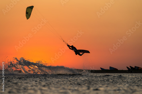 Professional kiter rides in the ocean against the background of incredible setting sun