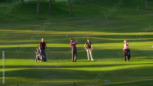 WS Four golfers on fairway, young man playing ball towards camera