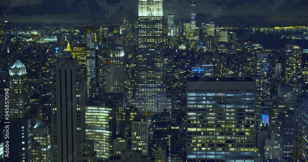 Panning shot over a skyscraper landscape illuminated by thousands of bright windows on New York City Empire State Building at night in Manhattan. Panning shot over a skyscraper landscape illuminated by thousands of bright windows on New York City Empire State Building at night in Manhattan.