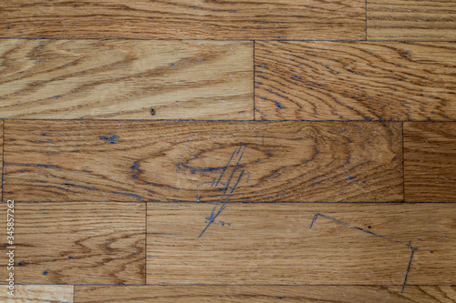 Inside the living room of a house. A parquet floor marked by dust, scratches and dog hair.