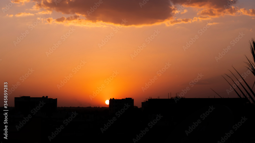 a sunset in city buildings silhouette