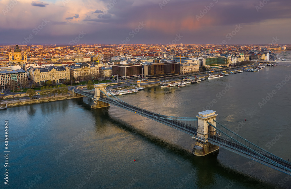 Obraz premium Budapest, Hungary - Aerial view of the Szechenyi Chain Bridge at sunset with colorful sky and St.Stephen's Basilica. The bridge and the streets are totally empty due to 2020 Coronavirus quarantine