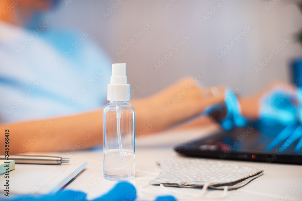 Coronavirus concept. Woman in quarantine for coronavirus covid-19 working from home. Protective mask and Sanitizer spray on the working place Coronavirus concept. Woman in quarantine for coronavirus covid-19 working from home. Protective mask and Sanitizer spray on the working place