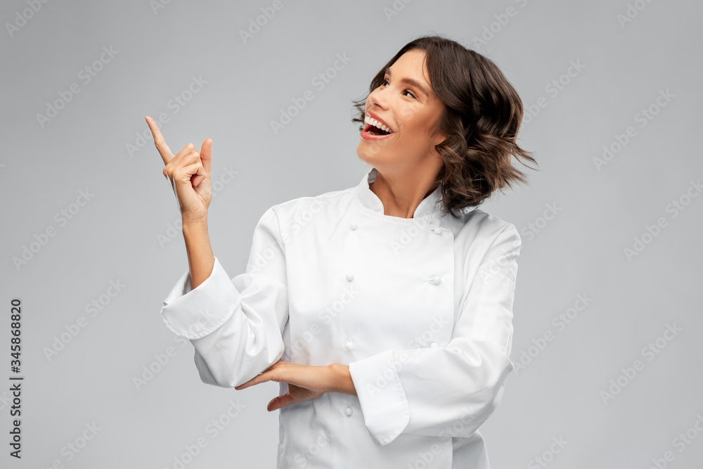 cooking, advertisement and food concept - happy smiling female chef in toque pointing finger up over grey background cooking, advertisement and food concept - happy smiling female chef in toque pointing finger up over grey background