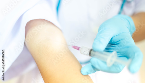 Doctor injecting drug dose into his arm by using syringe.