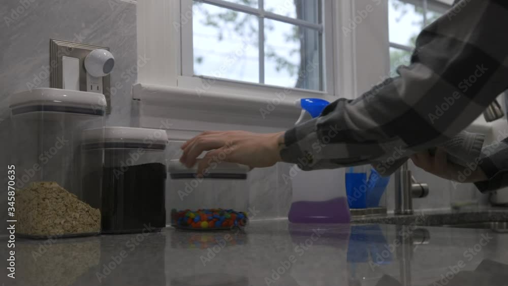A man cleans containers in his kitchen with sanitizing spray. Cleaning surfaces was a common practice to help stop the spread of COVID-19 during the pandemic of 2020. A man cleans containers in his kitchen with sanitizing spray. Cleaning surfaces was a common practice to help stop the spread of COVID-19 during the pandemic of 2020.
