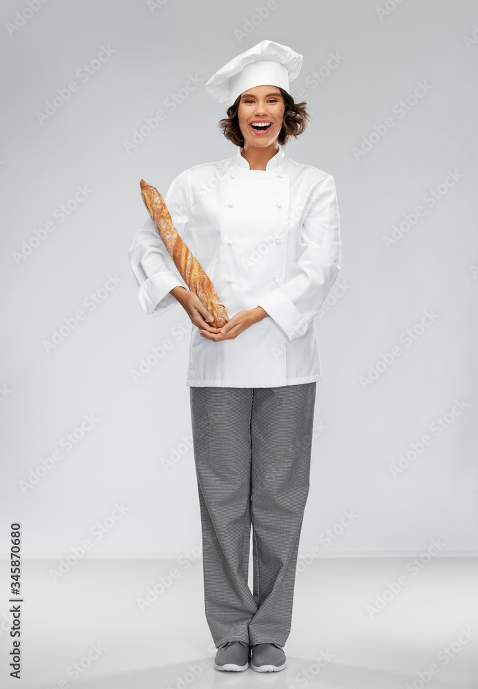 cooking, culinary and bakery concept - happy smiling female chef or baker in toque holding french bread or baguette over grey background