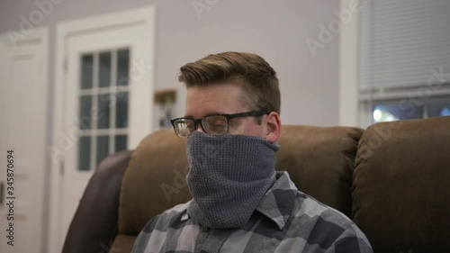 A frustrated young man with foggy glasses while wearing a face mask. Wearing face coverings was recommended to help flatten the curve of COVID-19 during the pandemic of 2020. photo