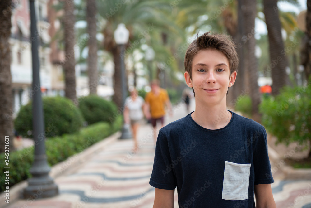 Handsome young boy looking at camera over promenade of Alicante. Beautiful calm smiling teen boy at Mediterranean coast in Spain. Travel, summer vacation, tourism, teenage lifestyle. Handsome young boy looking at camera over promenade of Alicante. Beautiful calm smiling teen boy at Mediterranean coast in Spain. Travel, summer vacation, tourism, teenage lifestyle.