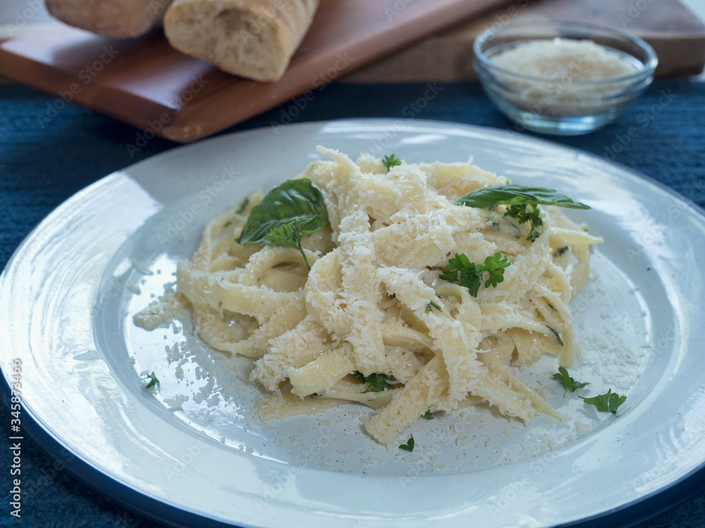 Pasta Alfredo Serving on Plate on Blue with Bread Horiz