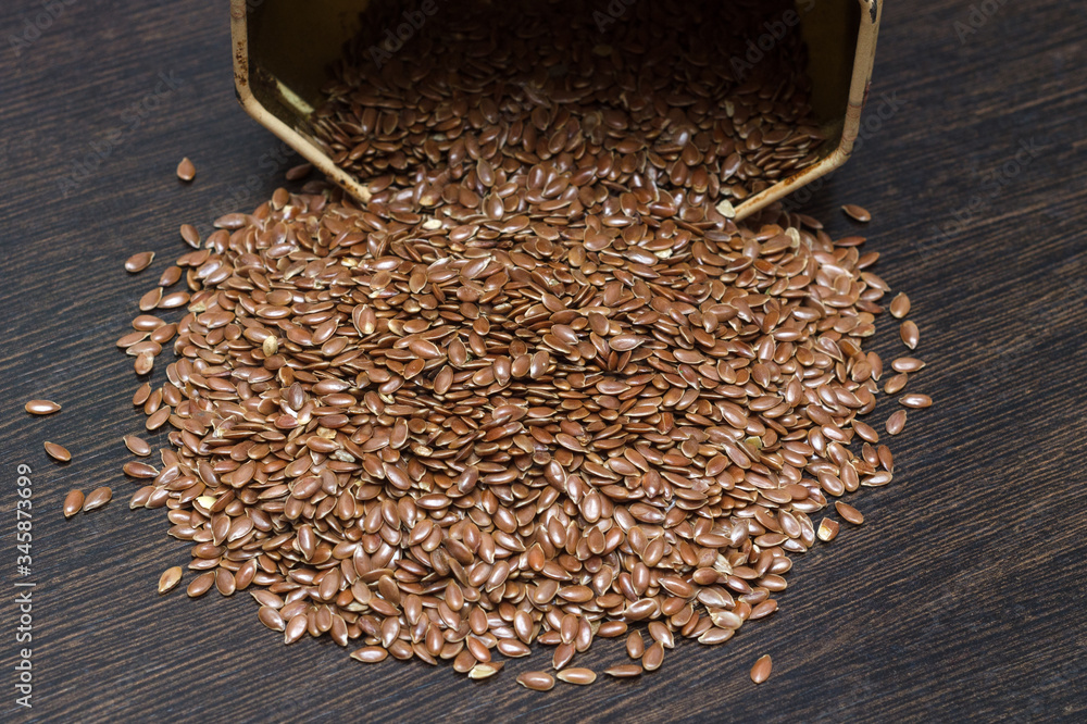 flax seeds sprinkled on a dark wooden table flax seeds sprinkled on a dark wooden table
