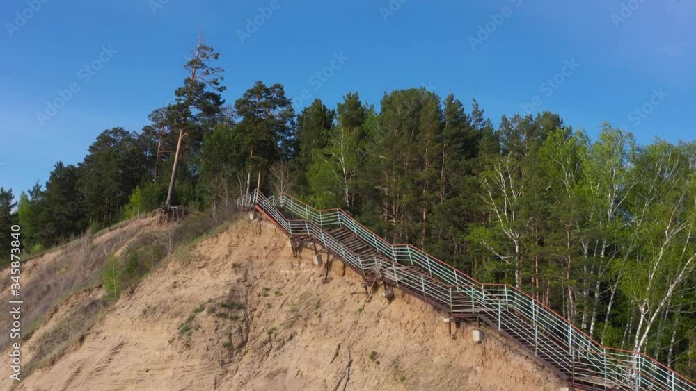 An old rusty and crooked staircase leads to a dense pine forest. Footage from a quadrocopter An old rusty and crooked staircase leads to a dense pine forest. Footage from a quadrocopter