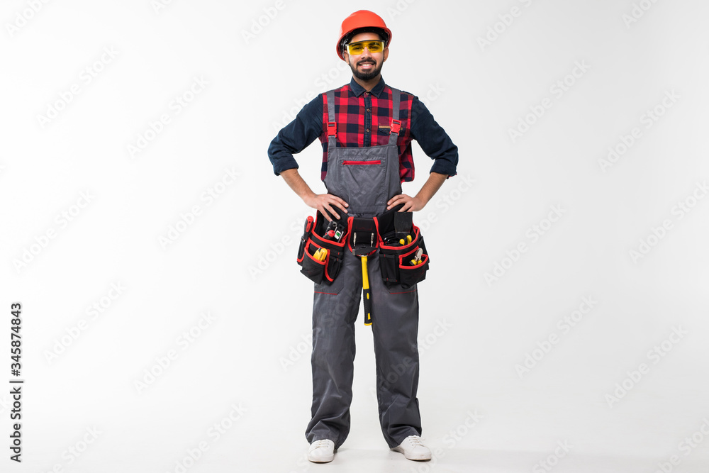 Portrait of happy young indian male construction worker with tool belt isolated on white background Portrait of happy young indian male construction worker with tool belt isolated on white background