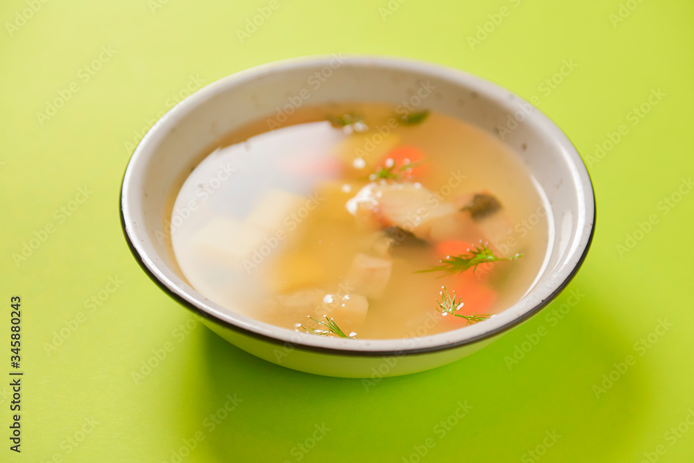 Delicious stew soup with meat and vegetables served in a white bowl over bright green background. Healthy diet. Delicious stew soup with meat and vegetables served in a white bowl over bright green background. Healthy diet.