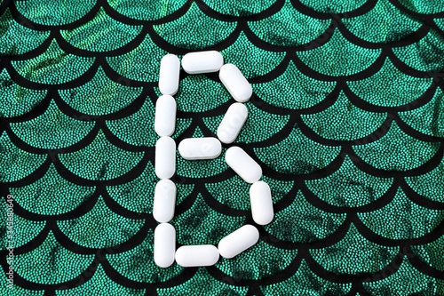 Obraz na płótnie Alphabet made of pills on a green and black background. Vitamins on a background of scales. Abc from drugs. Letter B made from pills. Capital letter B of medicines w salonie