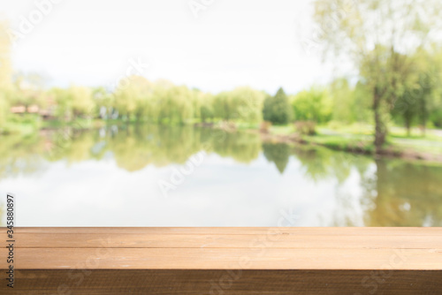 Empty wooden deck table with park bokeh background.