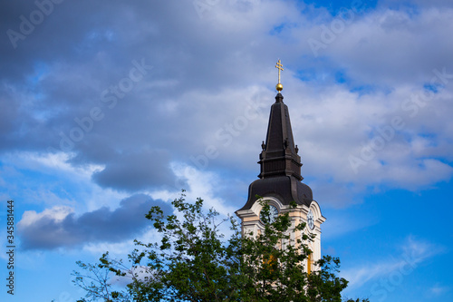 Blue sky and great tonal range clouds, clear weather, church and bell tower covered with a tree at Kecskemét city, Hungary