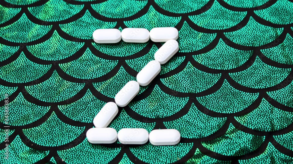 Alphabet made of pills on a green and black background. Vitamins on a background of scales. Abc from drugs. Letter Z made from pills. Capital letter Z of medicines