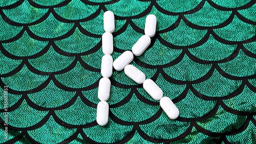 Obraz na płótnie Alphabet made of pills on a green and black background. Vitamins on a background of scales. Abc from drugs. Letter K made from pills. Capital letter K of medicines w salonie