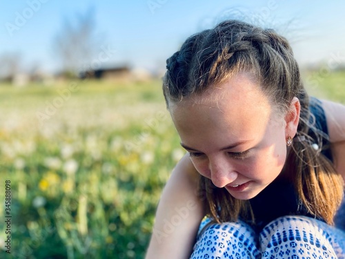 a teenage girl with pigtails in summer dress in dandelion meadow