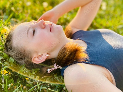 a teenage girl with pigtails in summer dress lying on green grass